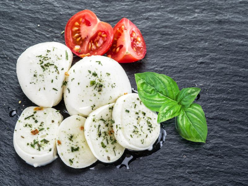 Mozzarella, basil and tomato on a gray slate background