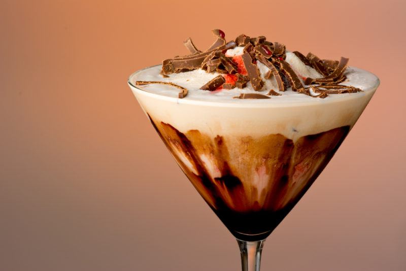 A mudslide cocktail against a colored background with chocolate sauce