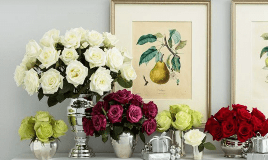 Multiple bouquets of flowers sitting on a back table all in silver vases