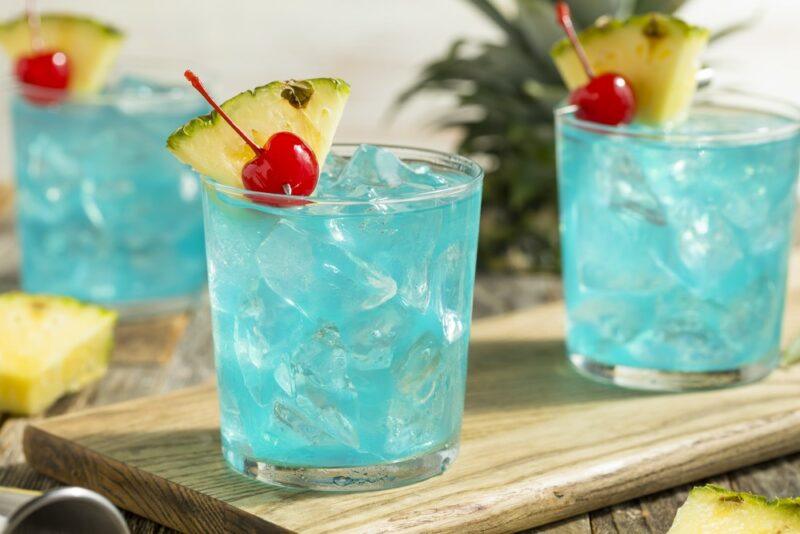 Three glasses containing a blue Hawaii cocktail with ice