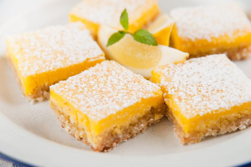 A white plate with 5 or 6 lemon bars