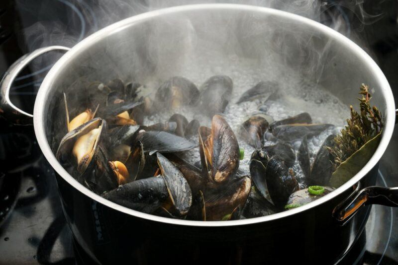 A stainless steel pot with mussels cooking