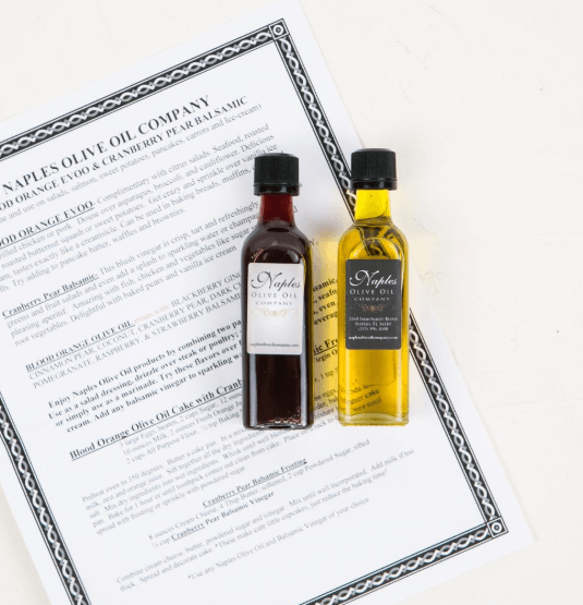 Naples Olive Oil Company | Food For Net A piece of paper with text, a bottle of olive oil and a bottle of balsamic vinegar.