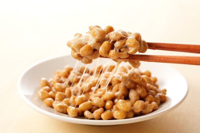 A white bowl of natto with chopsticks