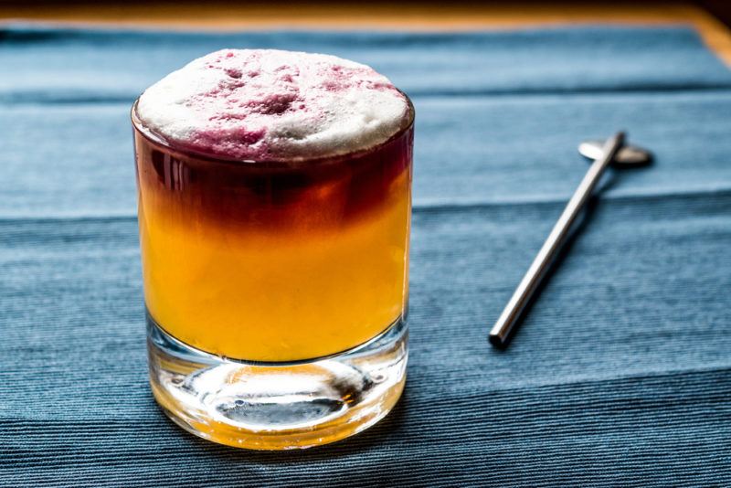 A two-toned New York sour in a glass on a blue table