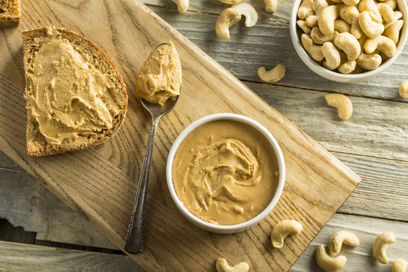 A white bowl of nut butter, with spread and spoon