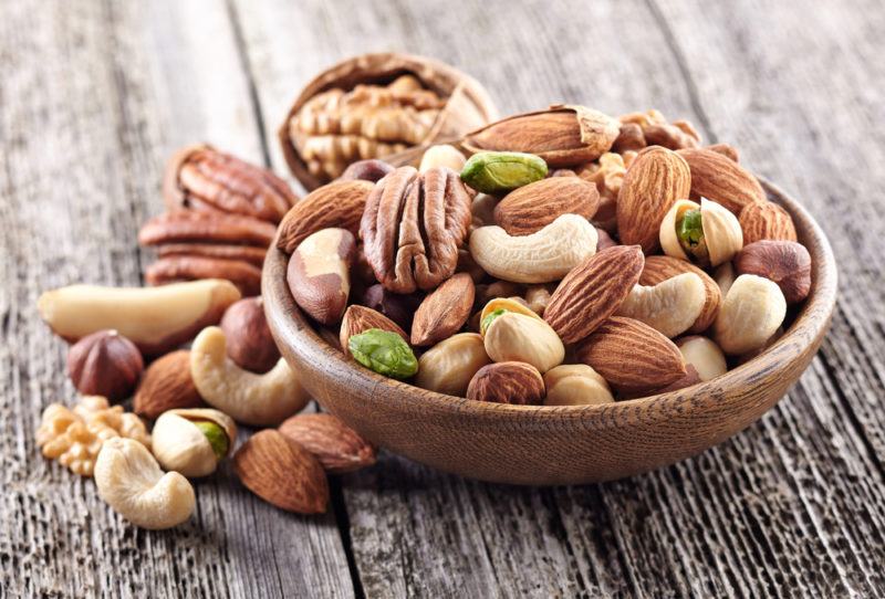 A selection of nuts in a bowl on a wooden table