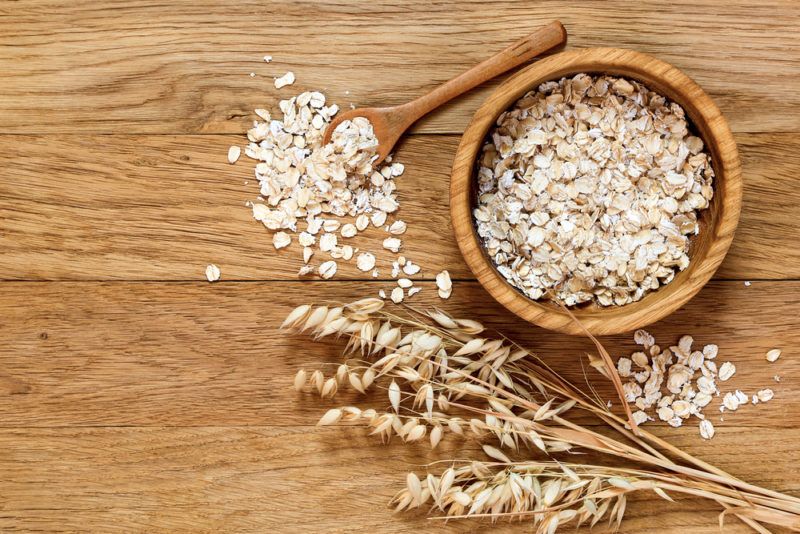 A bowl of oats and oats on a wooden spoon