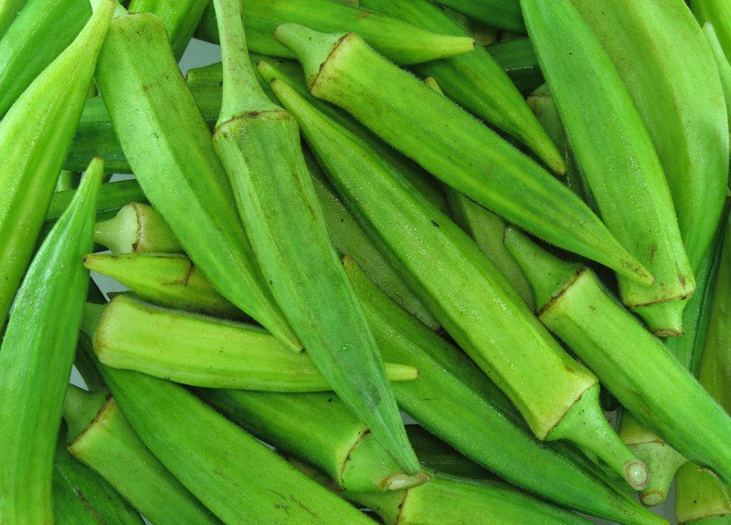 This photo shows a closeup of several green okra seed pods.