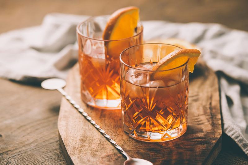 Two old fashioned cocktails on a wooden board