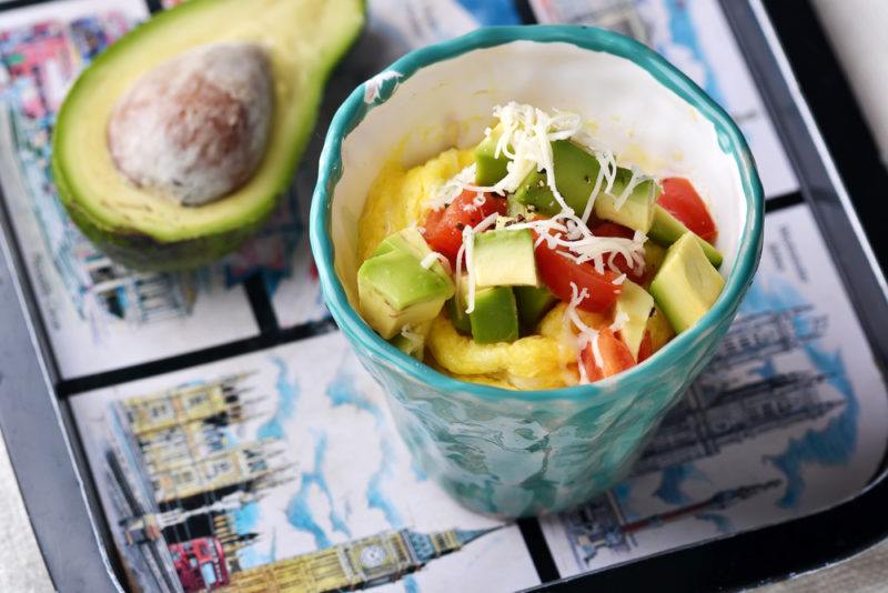 A ceramic mug to go in the microwave containing omelet ingredients