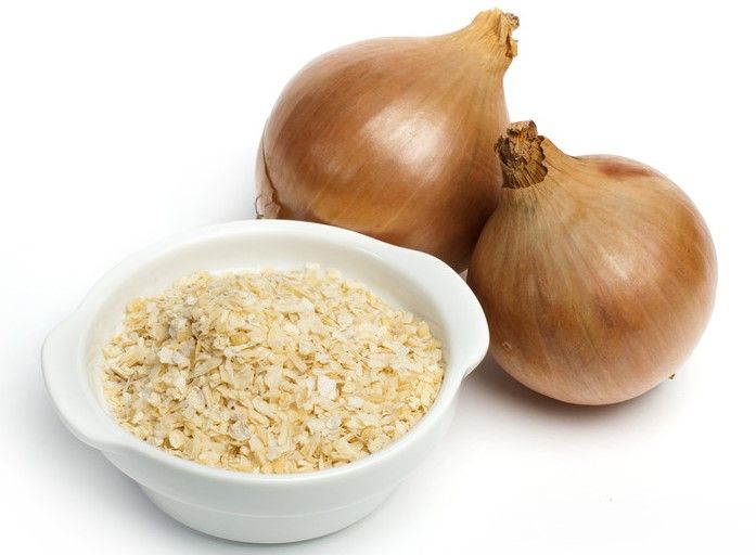 a couple of fresh onions with a small white bowl full of onion powder