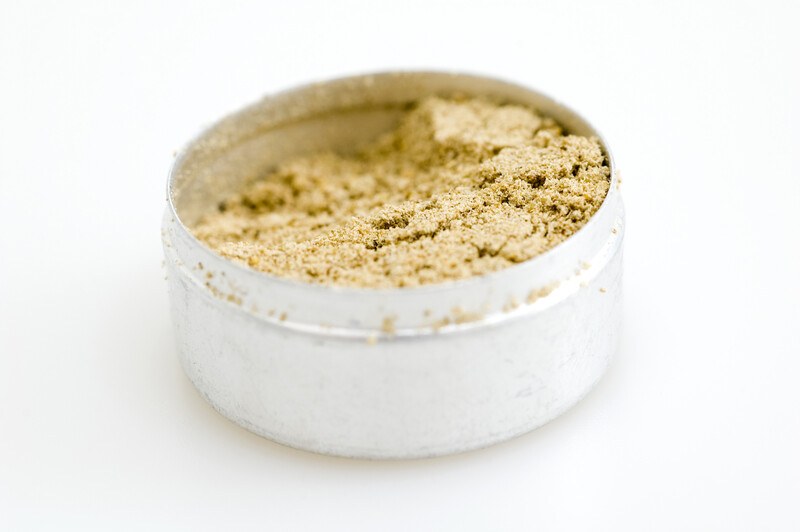 closeup image of onion powder in a small round tin container on a white background