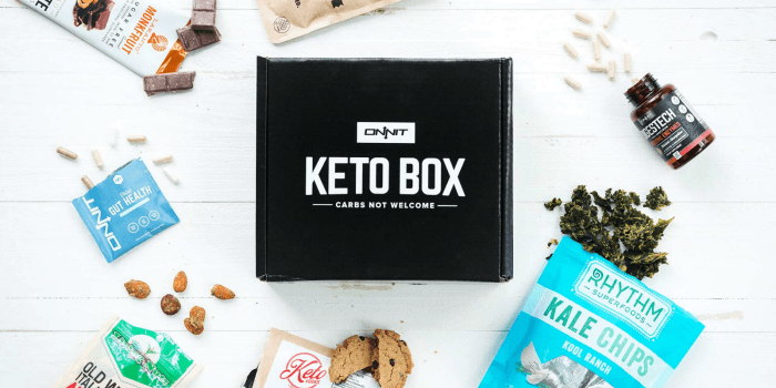 A black Onnit Keto box with various snacks surrounding it, on a white table