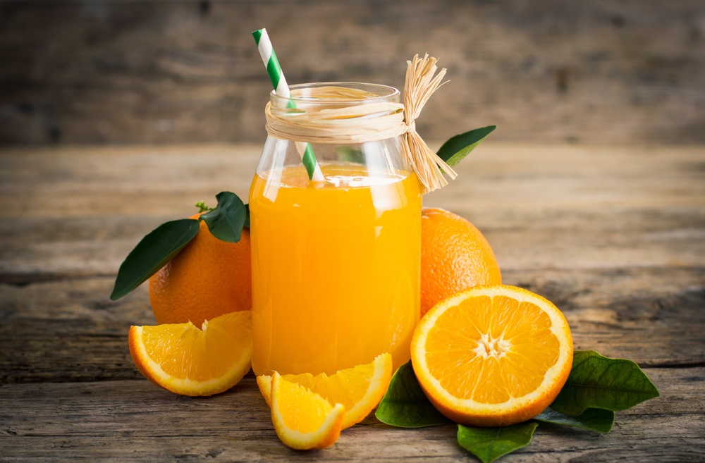 A glass of orange juice with oranges