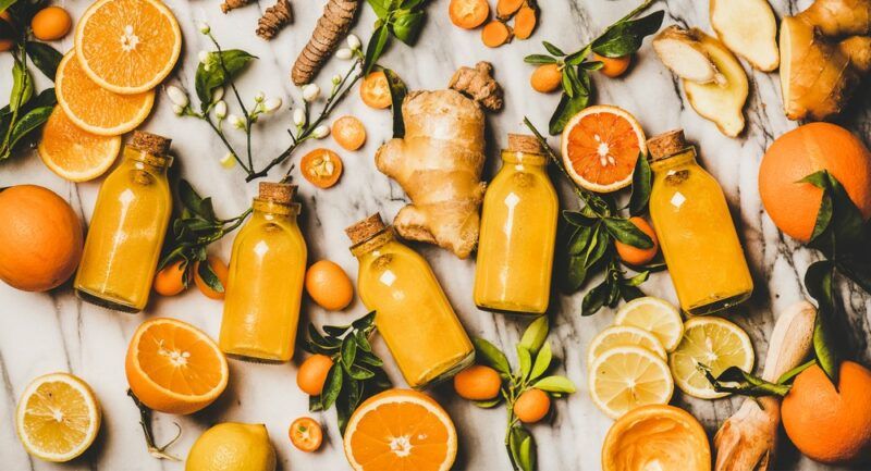 A selection of orange and turmeric shots with oranges on a table