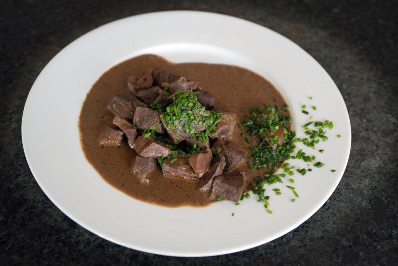 Cooked kidney on a white plate with gravey