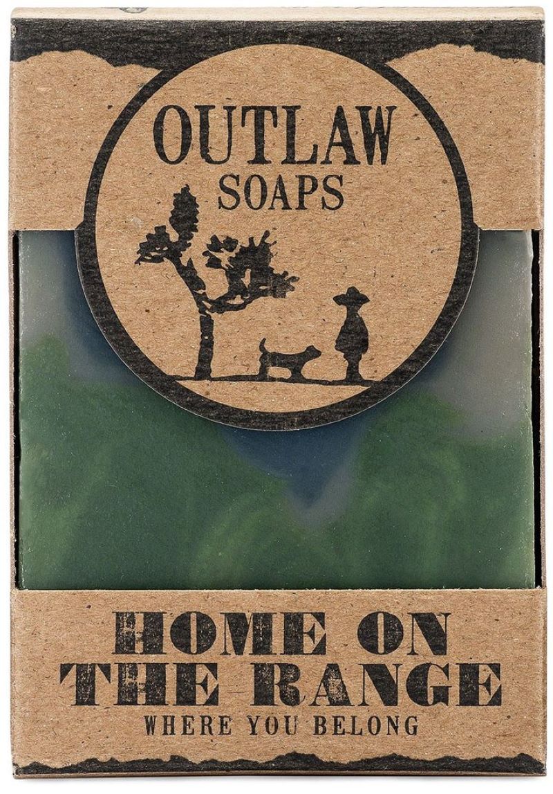 Green swirl soap with navy center in a card board box with a dye cut to see the soap inside.
The cardboard has been stamped with Outlaw Soaps with a tree, dog, and person silhouetted. 
The bottom of the box says, "Home on the Range Where you Belong"