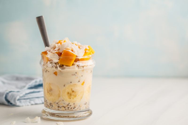 A jar of tropical overnight oats that uses cubed mangos and bananas as some of the main ingredients