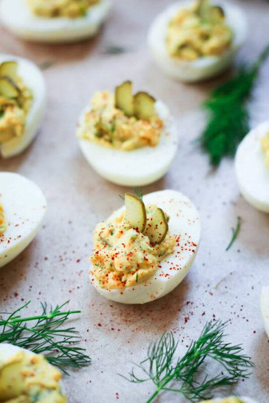 A selection of pickled eggs on a plate, garnished with pickle slices