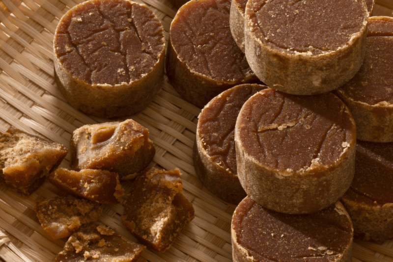 A woven basket with various rounds of hard palm sugar, plus a piece that has been broken into smaller pieces.