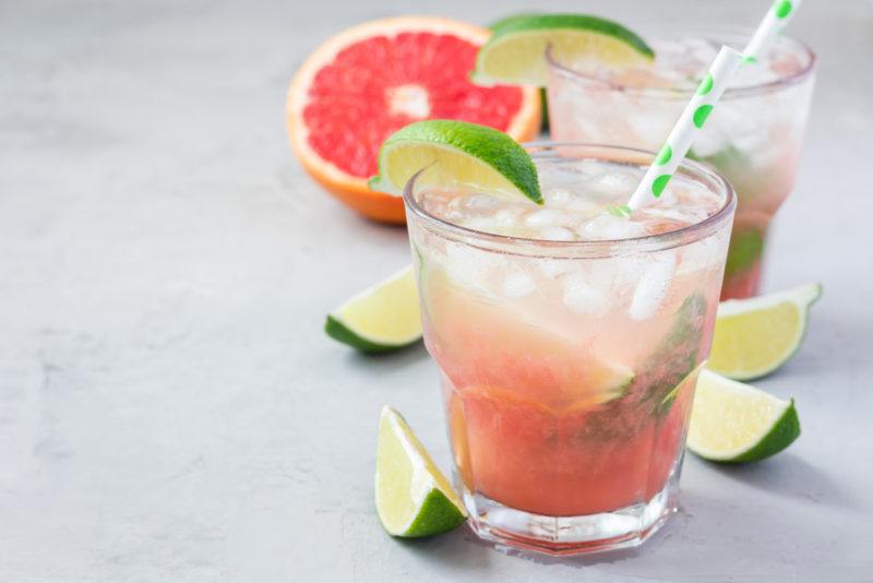 A paloma cocktail with grapefruit soda and lime wedges