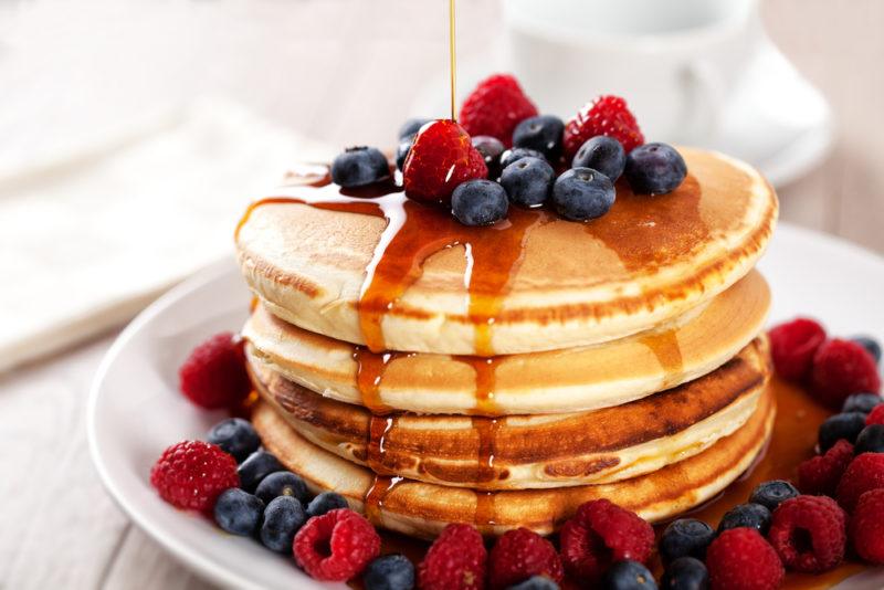 A stack of pancakes with berries and syrup