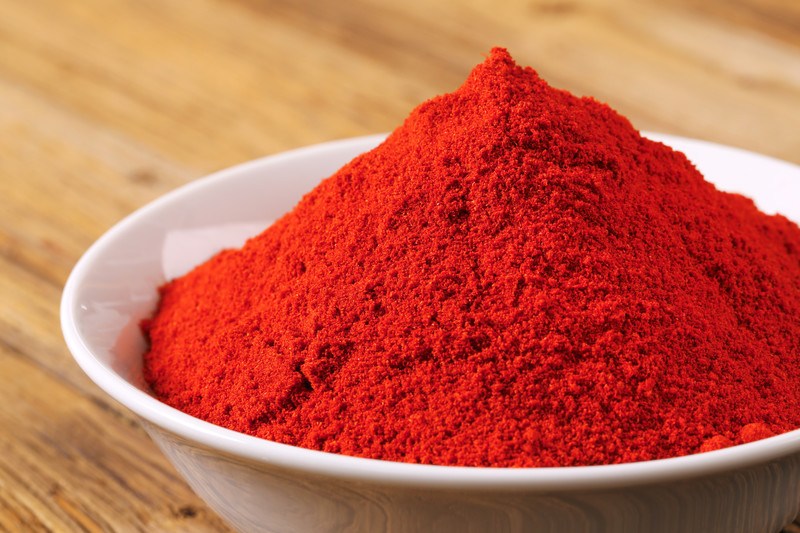 closeup image of a white ceramic bowl full of paprika powder