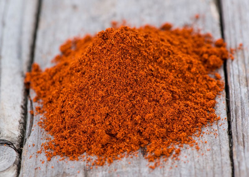 closeup image of a mound of paprika on an aged-wooden surface