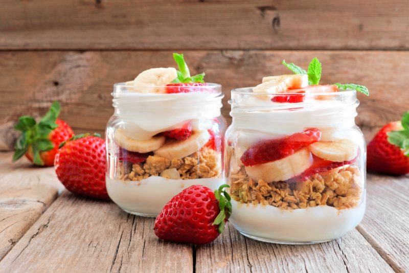 Two glass jars that contain yogurt granola parfaits