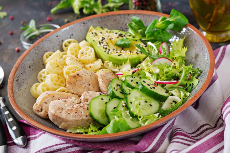 A bowl with pasta, avocado and other healthy ingredients