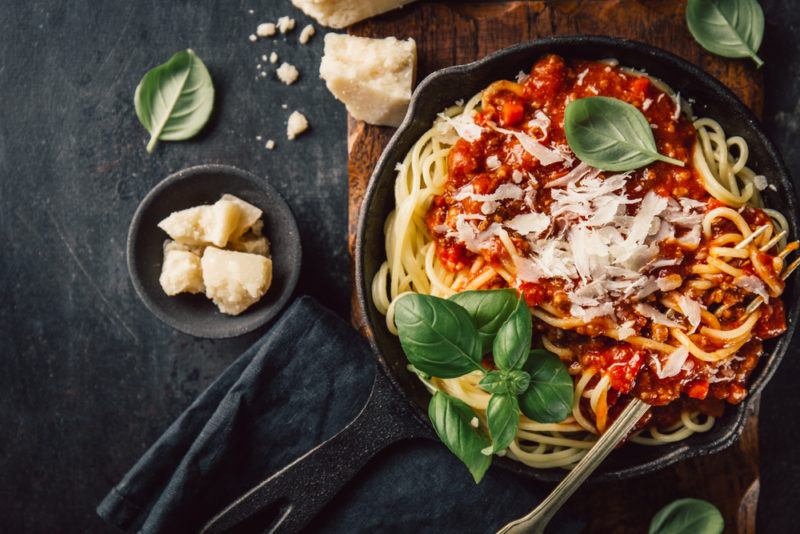 A cast iron pan with pasta and marinara sauce and parmesan