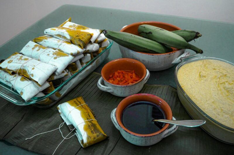 A table with a dish of prepared pasteles and all the ingredients used to make them