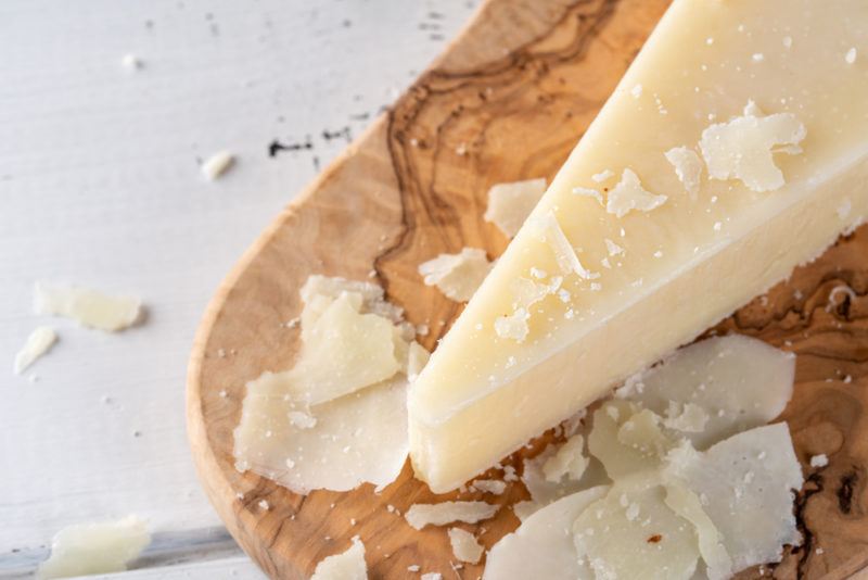 Pecorino Romano cheese with shaved pieces on a wooden board