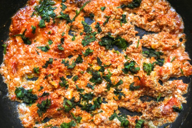 A fry pan with a Persian omelet with green vegetables and other ingredients