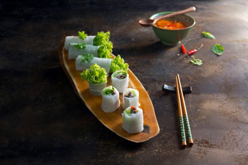 A wooden tray with pho cuon rolls and some chopsticks