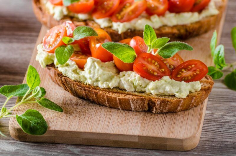 Pieces of sliced bread with goats cheese, cherry tomatoes, and herbs