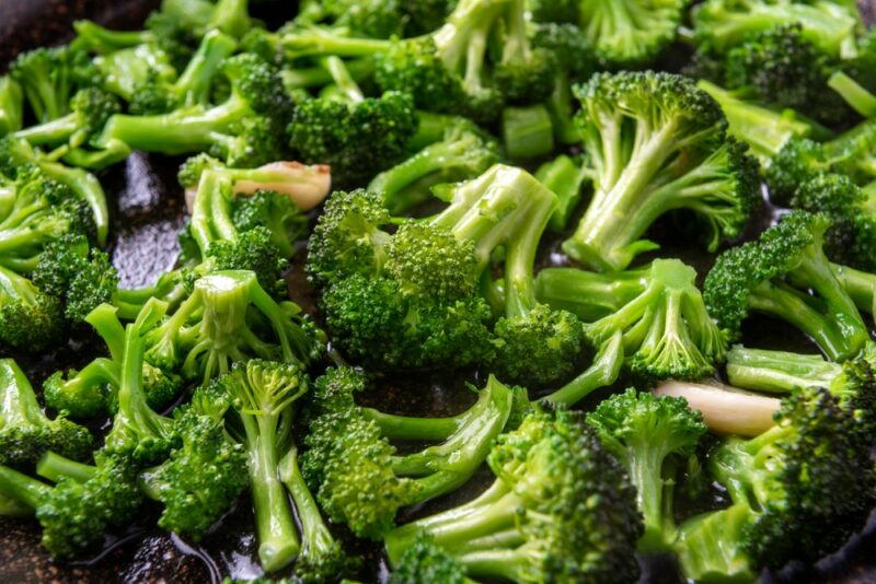 A large pile of broccoli pieces on a dark table