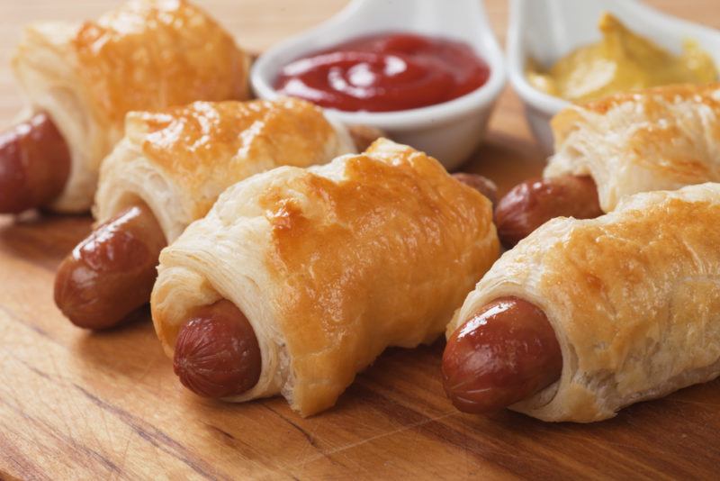 A wooden board with cooked pigs in a blanket