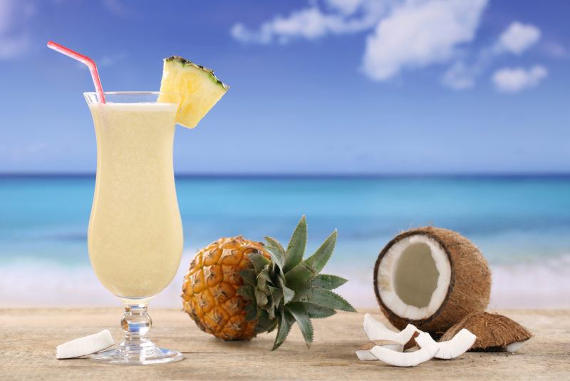 A pina colada on a beach with a pineapple and a coconut