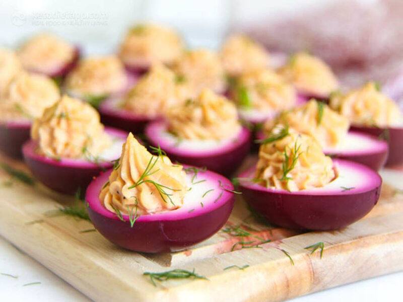 A wooden tray with dark pink pickled eggs