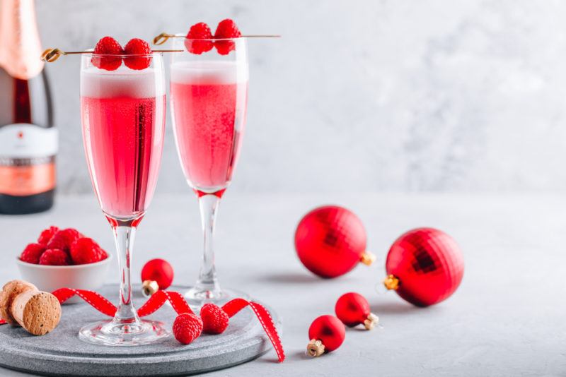 Two pink raspberry mimosas on a tray with baubles