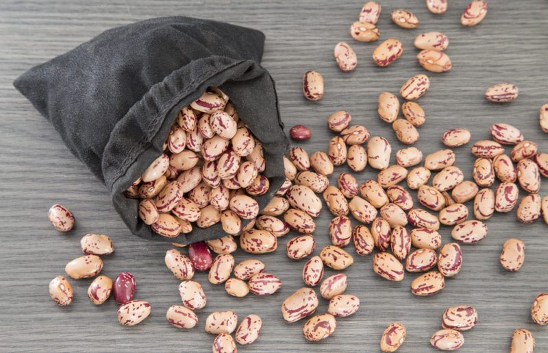 A black bag of pinto beans spilling out onto a table