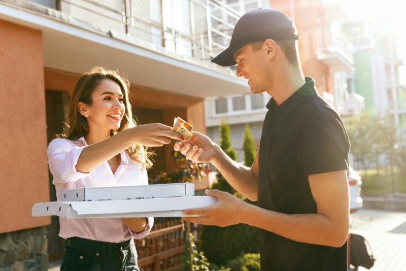 A young man delivering pizza to a woman