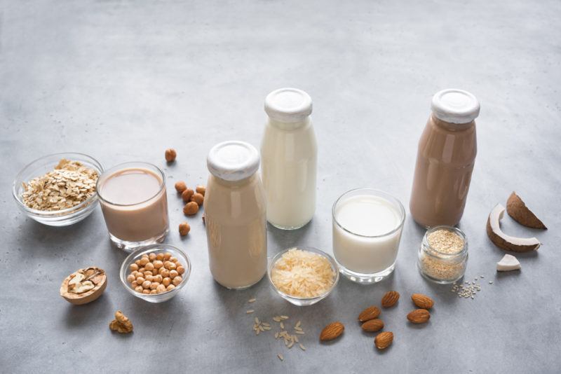 Various bottles of plant milk with nuts and the like in jars