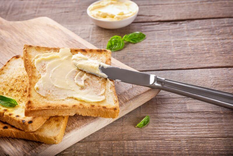 Three pieces of bread with plant-based butter, with a knife that's been used to put them on the bread