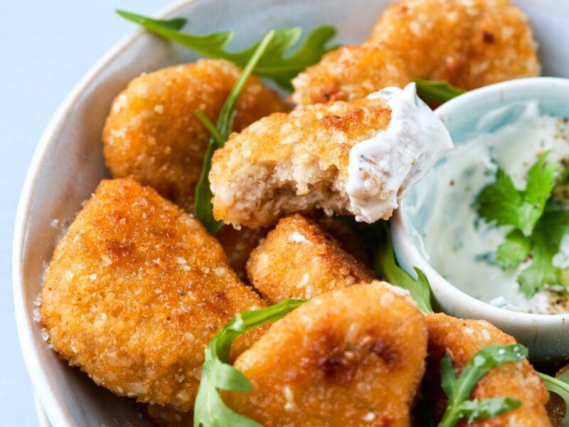 Plant-based chicken nuggets in a bowl with a small container of dip