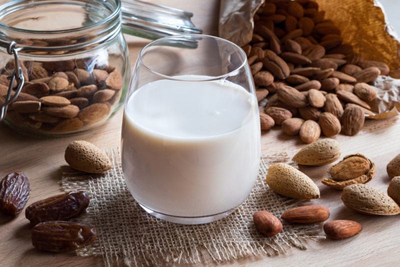 A glass of almond milk next to almonds