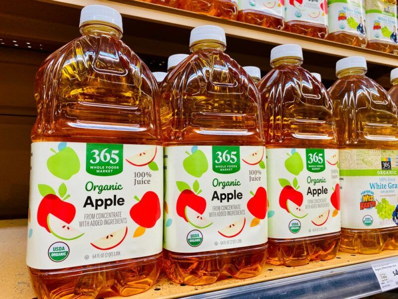 Plastic containers of apple juice on sale in a store