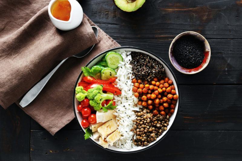 A bowl that is roughly split in half with rice down the middle and a selection of protein ingredients